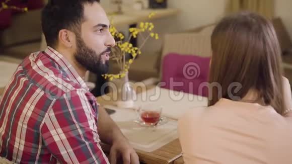 从侧面看英俊的中东男人在谈论和看着无法辨认的女朋友或妻子的爱视频的预览图