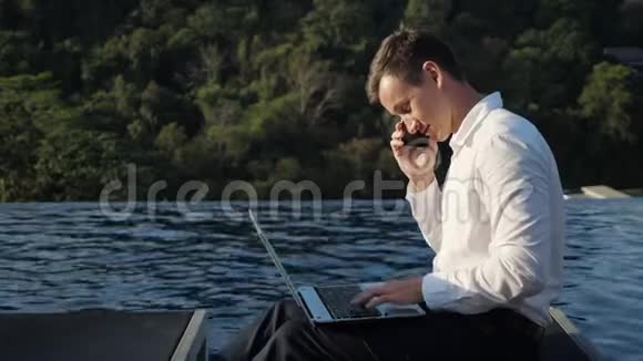 男人用笔记本电脑对着森林和游泳池打电话视频的预览图