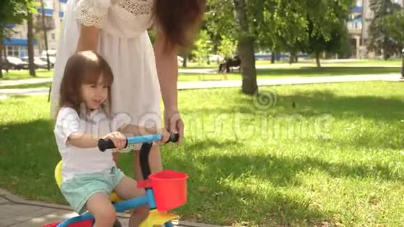 快乐妈妈教小女儿骑自行车妈妈在户外和孩子玩幸福家庭和视频的预览图