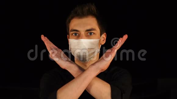戴着医疗面具的年轻人手势停止交叉双臂孤立在黑色上视频的预览图