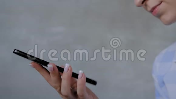 女士手持智能手机使用语音识别功能近距离观看视频的预览图