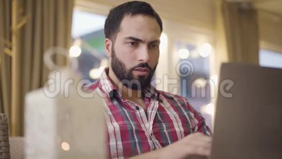集中的中东人坐在咖啡馆的桌子旁用手提电脑键盘打字的特写照片视频的预览图