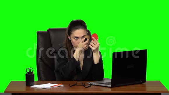工作场所的女商人化妆在脸上涂粉照着红镜子绿色屏幕慢慢视频的预览图