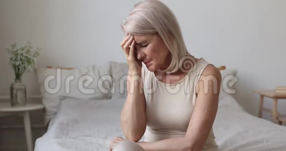 疲惫的老成熟女人应对早晨头痛的概念视频的预览图