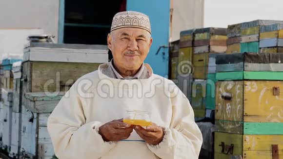 微笑老人用蜂蜜盛放容器的肖像有机生产视频的预览图