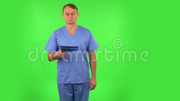 穿着蓝色外套的男医生用x光检查快照绿色屏幕视频的预览图