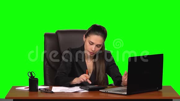 商务女性在笔记本电脑上工作将数据与计算器上的计数进行比较并在文档中输入绿色视频的预览图