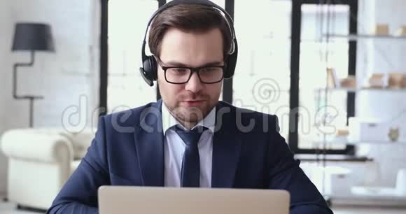 男性高管戴着耳机视频通过笔记本电脑摄像头通话视频的预览图