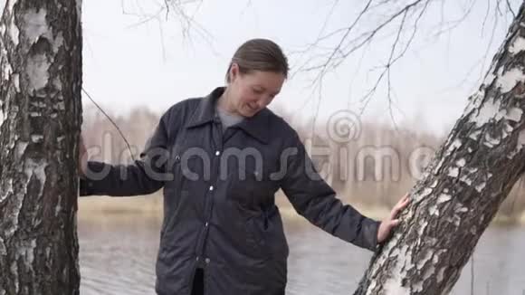 春天一个女人站在桦树附近的树林里视频的预览图