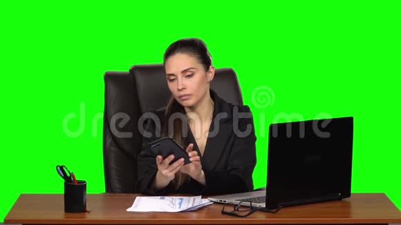 在笔记本电脑上工作的女人用手机接电话惊讶然后心烦意乱绿色屏幕慢动作视频的预览图