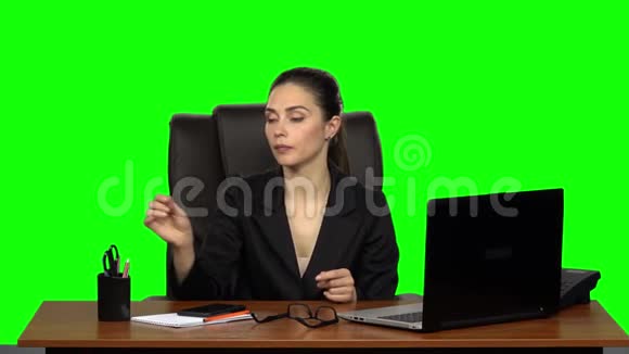 工作场所的女孩正在用笔记本电脑工作在电话上交谈在锯钉子绿色屏幕慢动作视频的预览图
