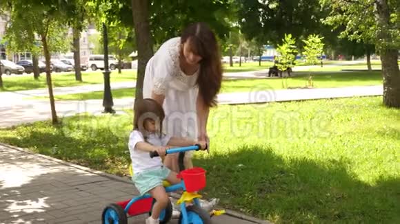 幸福家庭和童年的概念孩子学会骑自行车父母和小女儿在公园散步快乐视频的预览图