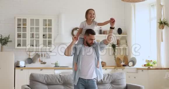 微笑的年轻爸爸带着兴奋的小女儿一起跳舞视频的预览图
