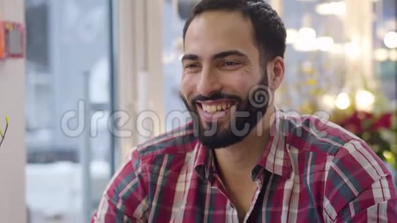 开朗的中东男人的特写脸大声笑出来在咖啡馆喝茶英俊胡子的肖像视频的预览图