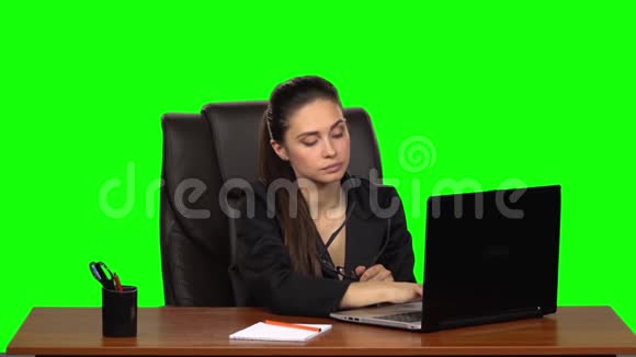 疲惫的女孩手里拿着眼镜在笔记本电脑上工作然后打哈欠绿色屏幕慢动作视频的预览图