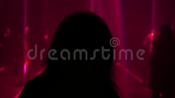 女人的剪影环顾四周欣赏黑暗房间里明亮的激光表演视频的预览图