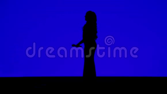 一位身材苗条的女歌手在舞台上的剪影蓝色背景上有麦克风视频的预览图
