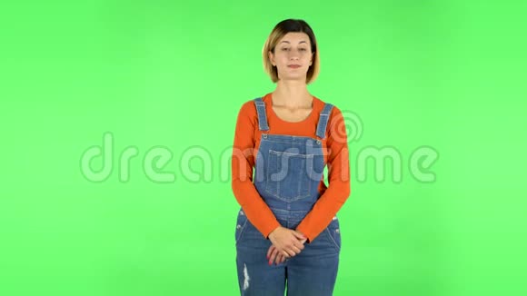 年轻女子无聊地站在那里等着绿色屏幕视频的预览图