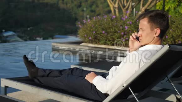 盖伊在日落时分在布什酒店的泳池边打电话视频的预览图