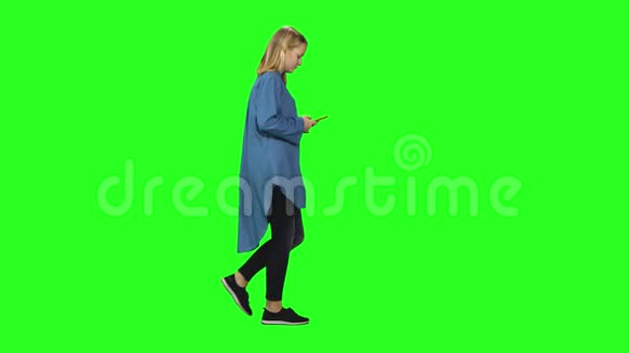 金发少女平静地走着在绿色屏幕上的手机上读着短信侧写视图视频的预览图