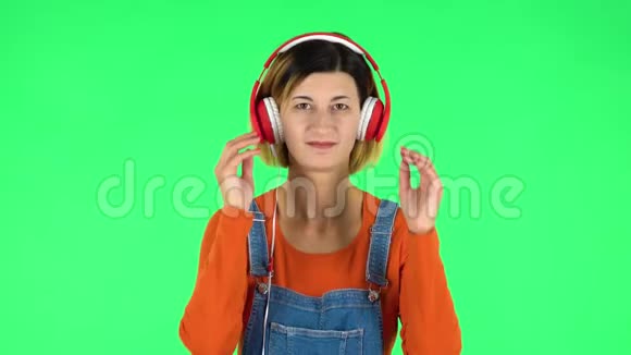快乐的女孩跳舞享受音乐在大红色耳机绿色屏幕视频的预览图