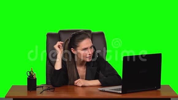 商务女孩戴着耳机用网络摄像头说话带着喜悦的情绪看着笔记本电脑绿色屏幕慢动作视频的预览图