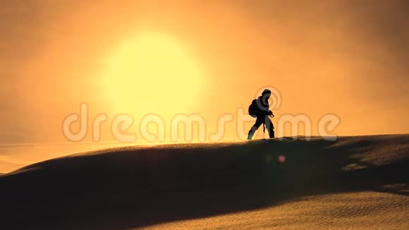 冬天的摄影师在黄色的日落中登上雪岭有照相机和三脚架的登山者视频的预览图