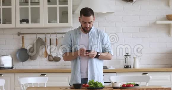 英俊的年轻人拿着手机拍着食物的照片视频的预览图