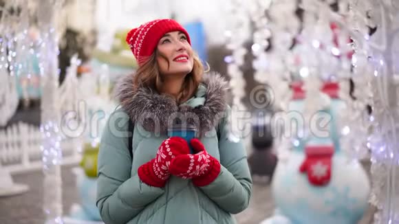美丽可爱的中年女孩卷发温暖的冬季毛衣站在背景镇广场视频的预览图