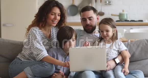 微笑的四口之家使用笔记本电脑在家购物视频的预览图