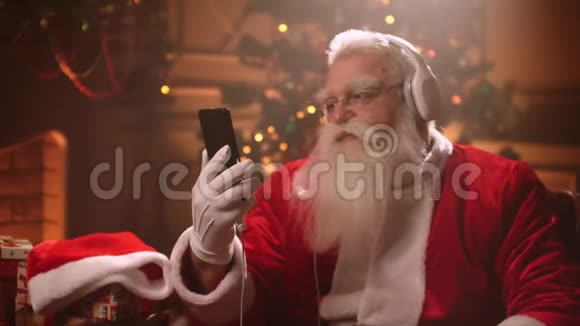 圣诞老人用耳机听圣诞音乐玩得很开心也很放松视频的预览图