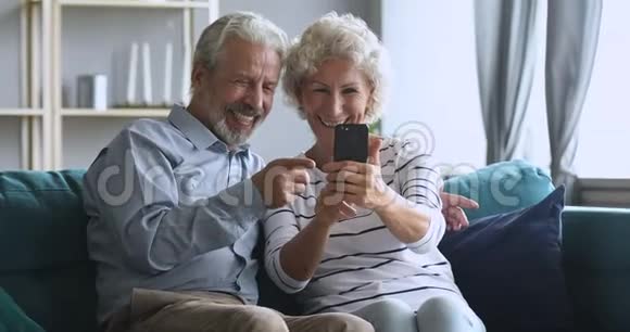 快乐的中年家庭玩得开心在智能手机上自拍视频的预览图