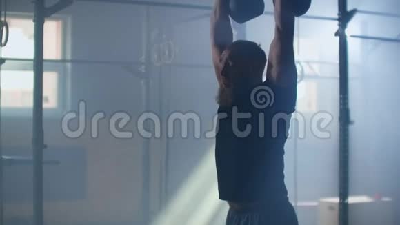 运动强壮的男性使用两个水壶铃进行健身锻炼在缓慢的运动交叉训练视频的预览图