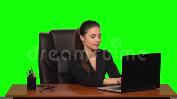 商务女性在笔记本电脑上工作开心地微笑着一边看着相机一边显示OK标志绿色屏幕慢慢视频的预览图