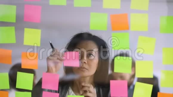 成熟的韩国女经理在彩色纸贴纸上写笔记视频的预览图