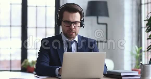 自信的商人戴着耳机在笔记本电脑上打电话视频的预览图