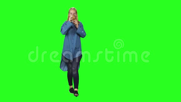 金发少女平静地走着在绿色的屏幕背景上喝着咖啡铬钥匙4k射击前景视频的预览图