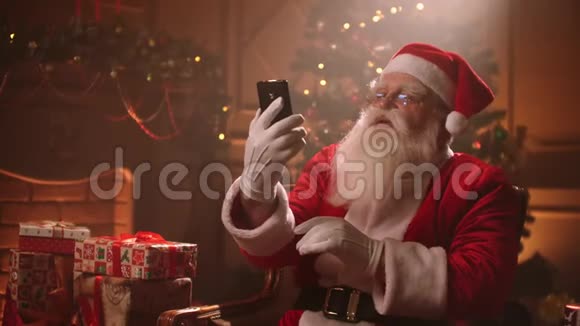 圣诞老人使用智能手机在举行会议时通过视频链接交谈圣诞老人和自拍相机视频的预览图