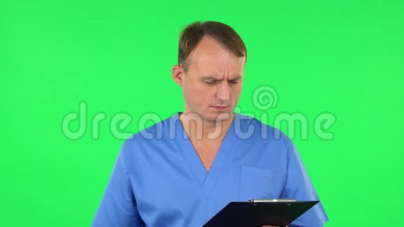 烦人的医生用pensil在黑色文件夹里填写文件绿色屏幕视频的预览图