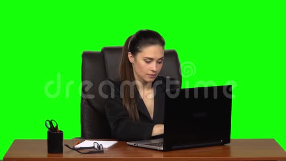 女孩热情地在笔记本电脑后面工作微笑着享受结果绿色屏幕慢动作视频的预览图