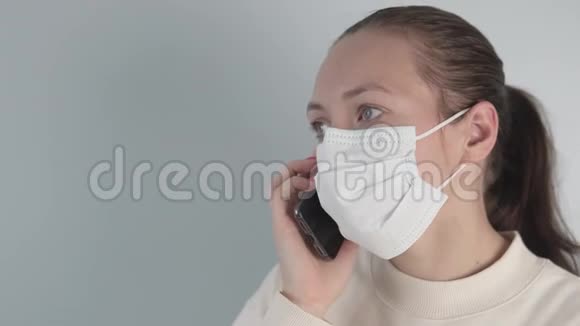 一个戴着医用防护面罩的女人正在用手机说话视频的预览图
