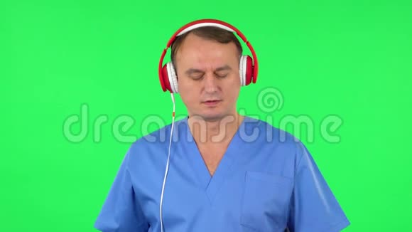 戴着红色大耳机的医务人员在手机上打开音乐绿色屏幕视频的预览图