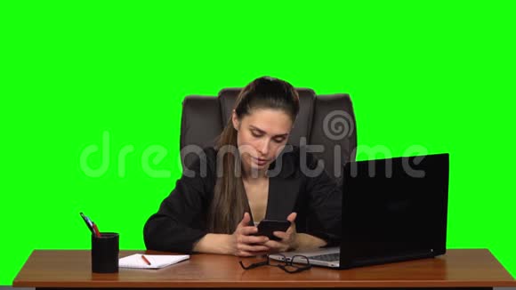 商务女性坐在办公桌前愤怒地在手机上写着一条信息绿色屏幕工作室慢动作视频的预览图