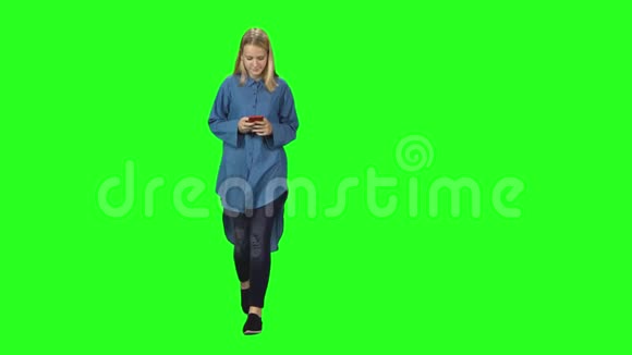 金发少女平静地走着在绿色屏幕上的手机上阅读短信前景视频的预览图