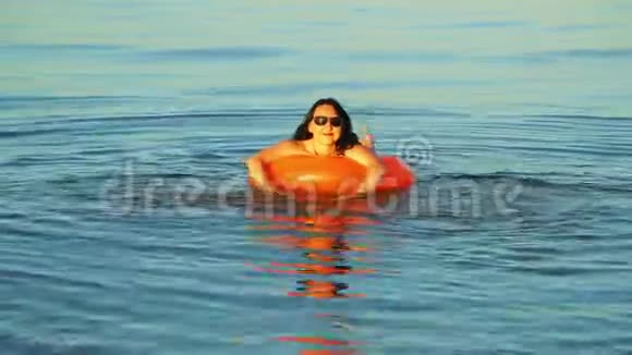 一位身穿泳装和眼镜的黑发女子在靠近海岸的海域游泳视频的预览图