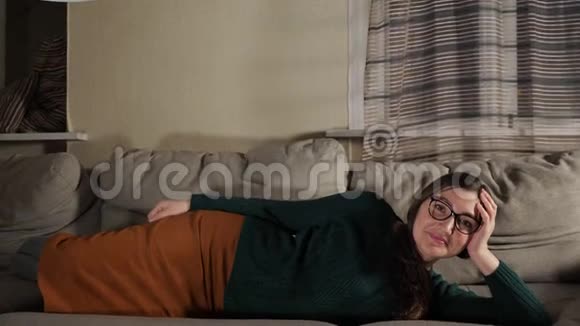年轻的黑发女人躺在沙发上视频的预览图