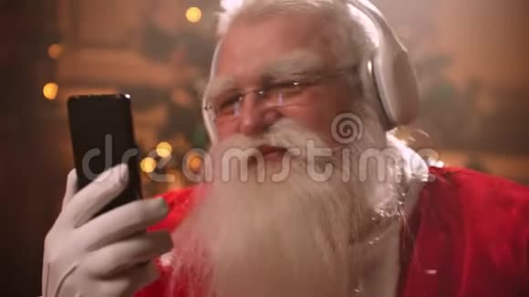 圣诞前夜一位留着白胡子的老人穿着圣诞老人服装听音乐新的圣诞老人视频的预览图