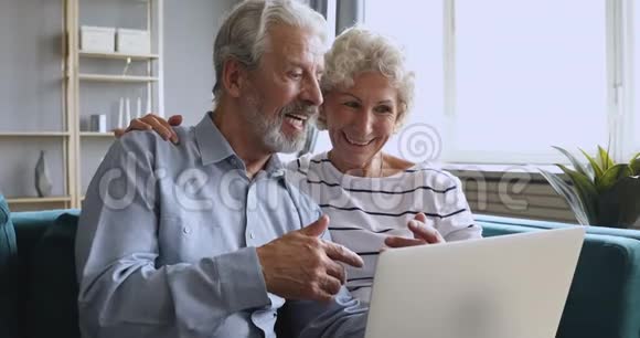 微笑60年代的女人拥抱愉快的丈夫解释电脑软件视频的预览图