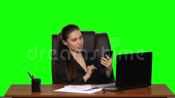 职场女性欣喜地看着手机上的照片绿色屏幕工作室慢动作视频的预览图