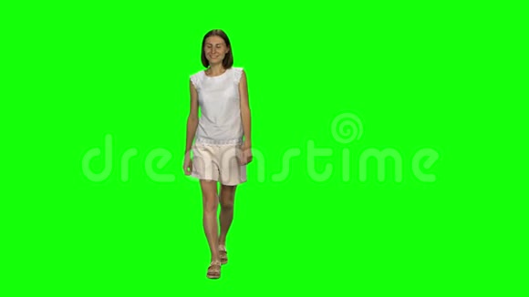 棕色头发和光滑发型的年轻女人平静地走着在绿色的屏幕上微笑铬钥匙前景视频的预览图